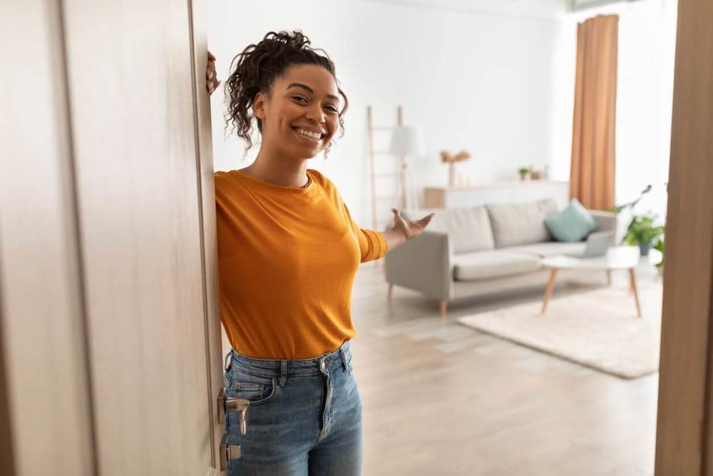 Woman standing at door welcoming jesture into home